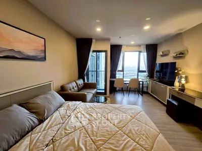 Modern studio apartment with cozy living area and balcony view.