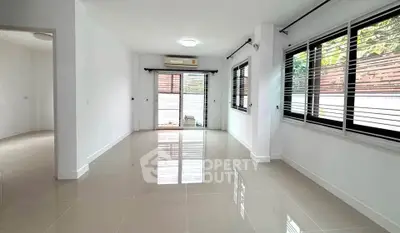 Spacious living room with large windows and glossy tiled floors in modern home.
