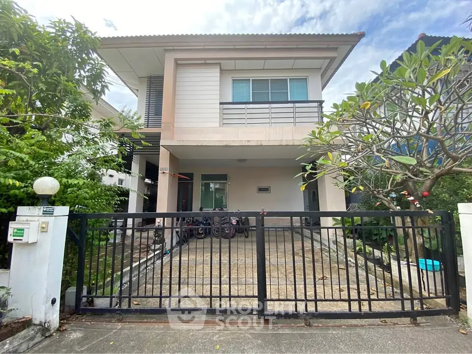 Charming two-story house with gated driveway and lush greenery in a serene neighborhood.