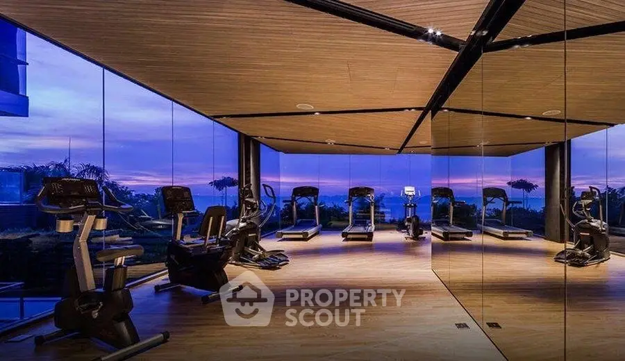 Luxurious gym with panoramic views and modern equipment at sunset.