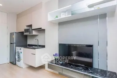 Modern apartment interior with sleek kitchen and living area featuring TV and washing machine.