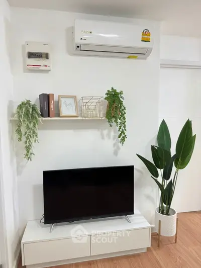 Modern living room with sleek TV unit, air conditioning, and stylish decor plants.