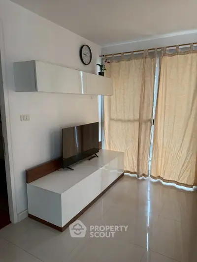 Modern living room with sleek TV stand and natural light from large windows.