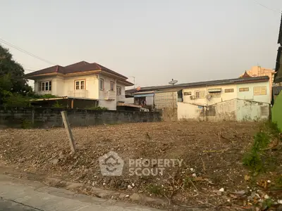 Vacant land plot in suburban area with nearby houses, ideal for new construction.
