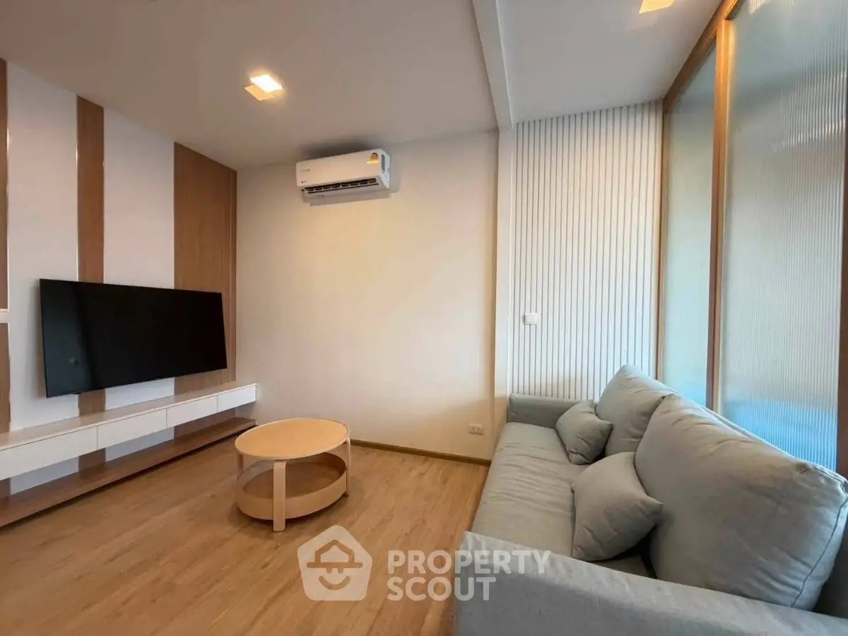 Modern living room with sleek design, featuring a wall-mounted TV, cozy sofa, and air conditioning.