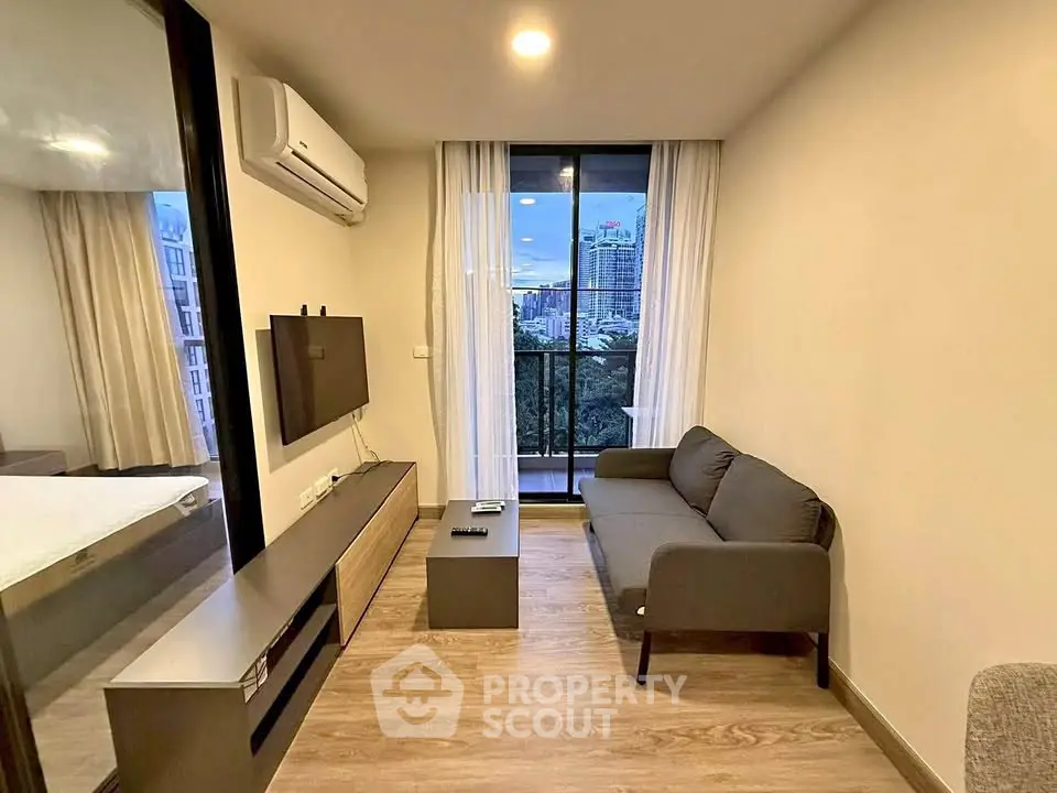 Modern living room with city view, featuring sleek furniture and large window for natural light.