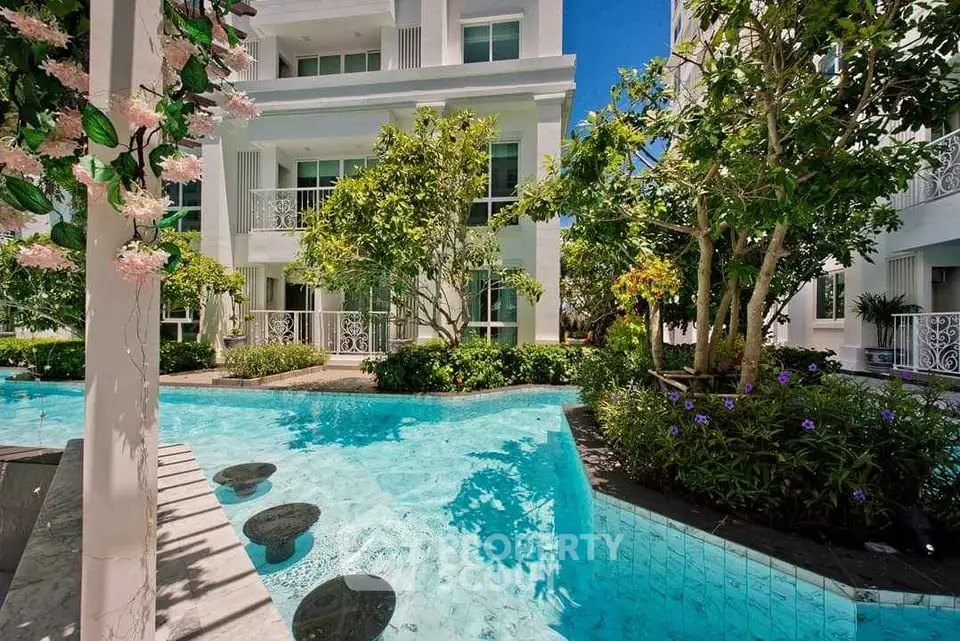 Luxurious apartment complex with stunning pool and lush garden landscaping.