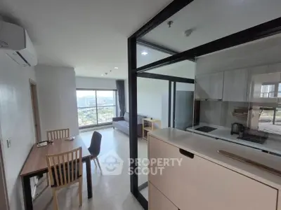 Modern open-layout living room with kitchen and city view, featuring sleek furniture and large windows.