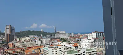 Expansive cityscape view from a high-rise balcony showcasing a vibrant urban environment with diverse architecture under a clear blue sky.