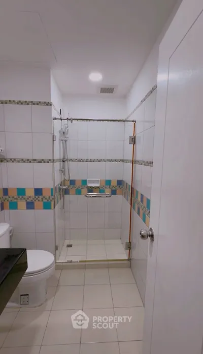 Modern bathroom with colorful tile accents and glass shower enclosure.