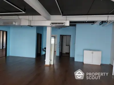 Spacious commercial space with polished wooden floors and high ceilings, featuring exposed ductwork for a modern industrial vibe, ideal for businesses seeking an open-plan layout.