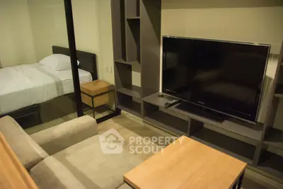 Modern studio apartment with cozy living area and bedroom separated by glass partition.