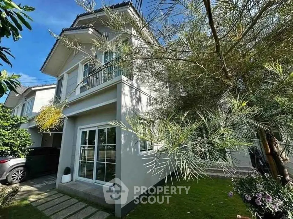 Charming two-story house with lush garden and driveway in a serene neighborhood.