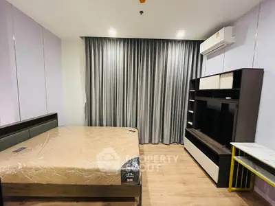 Modern bedroom with sleek furniture and air conditioning, featuring a cozy bed and stylish curtains.