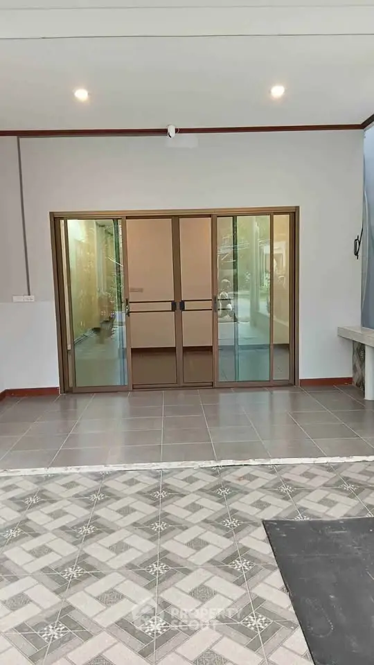 Modern home entrance with sliding glass doors and stylish tile flooring.
