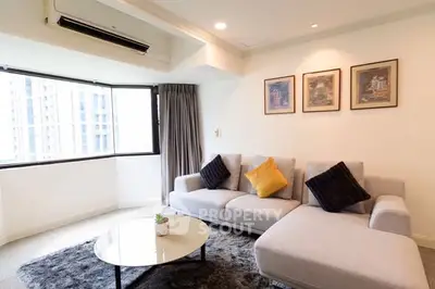 Spacious living room with modern sofa and large window view in urban apartment.