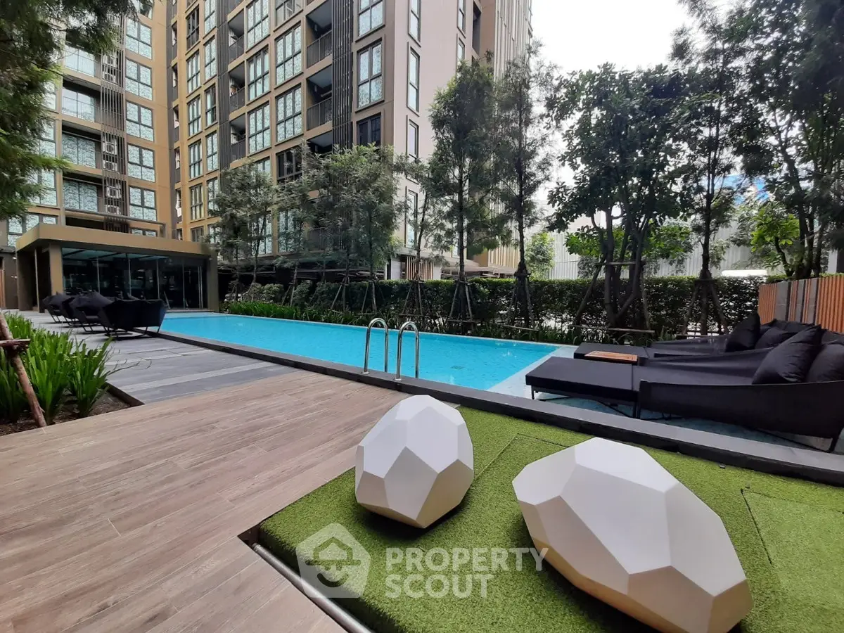 Luxurious apartment complex with modern pool and stylish outdoor seating area.