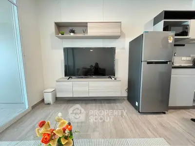 Modern living room with sleek TV unit and stainless steel fridge, perfect for contemporary urban living.