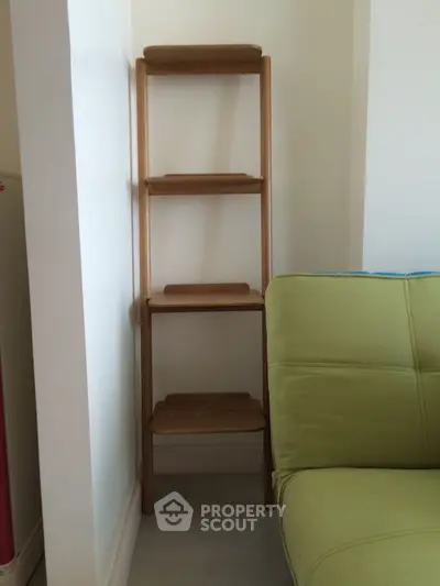 Compact wooden shelf in cozy living room corner with green sofa