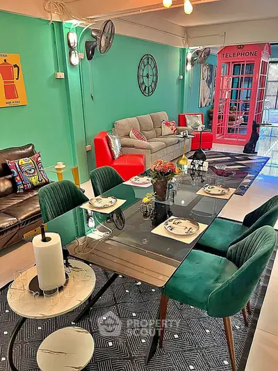 Stylish living room with vibrant decor and modern dining area, featuring unique telephone booth accent.