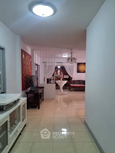 Spacious hallway leading to a stylish living area with elegant decor and tiled flooring.