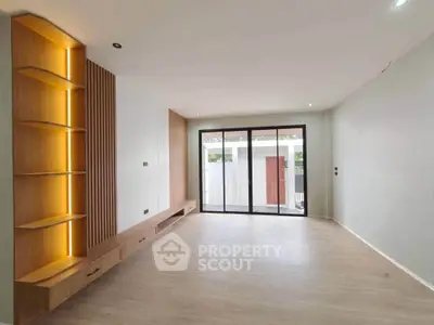 Spacious modern living room with built-in wooden shelves and large windows for natural light.