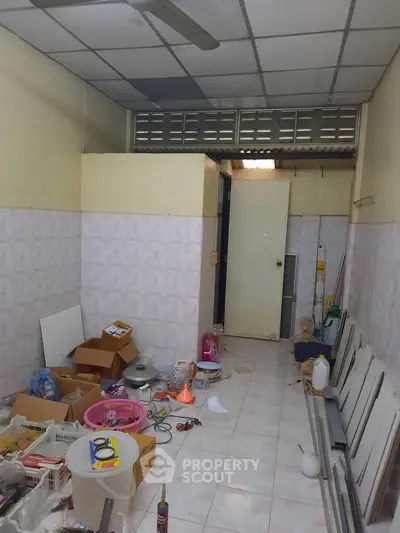 Cluttered storage room with scattered items and tiled walls