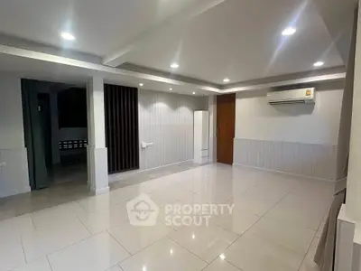 Spacious modern living room with sleek tile flooring and recessed lighting, featuring a wall-mounted air conditioner.