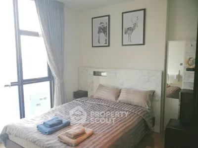 Modern bedroom with large window and stylish decor in urban apartment.