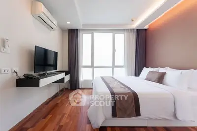 Modern bedroom with wooden flooring, large window, and sleek TV setup in a stylish apartment.