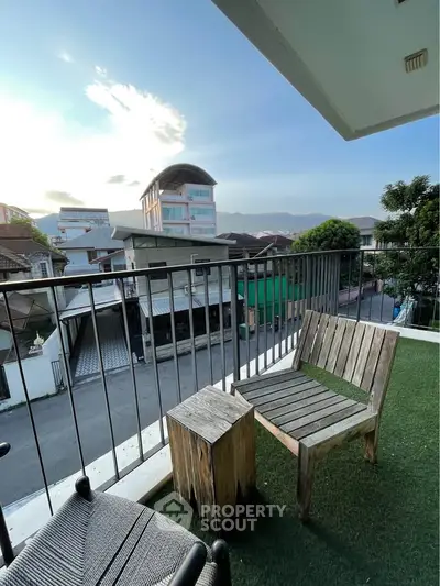 Charming balcony with wooden furniture offering a scenic view of the neighborhood and distant mountains.