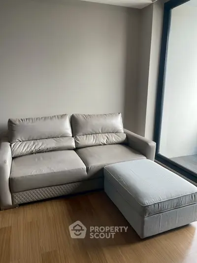 Modern living room with sleek leather sofa and large window for natural light.