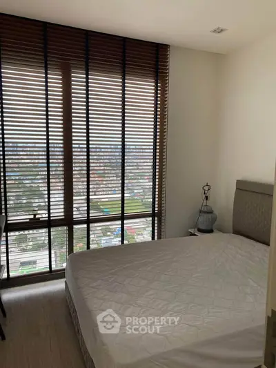 Cozy bedroom with large window offering stunning city view and natural light.