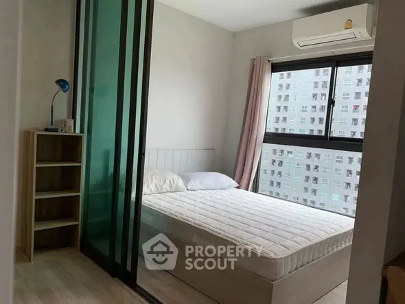 Modern bedroom with large window and air conditioning in urban apartment.