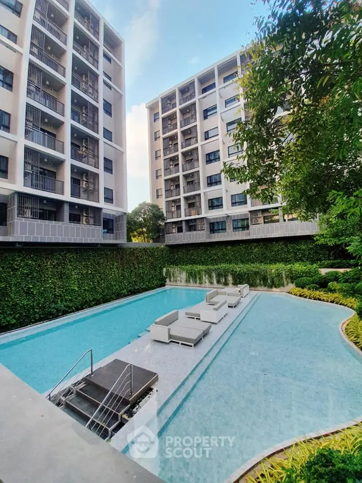 Luxurious condo pool area with modern architecture and lush greenery