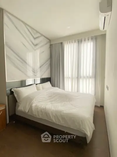 Modern bedroom with large windows and stylish decor, featuring a comfortable bed and natural light.