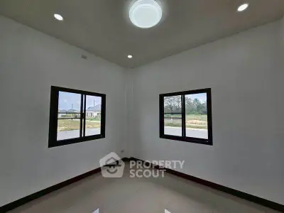 Spacious corner room with large windows and natural light, ideal for versatile living space.