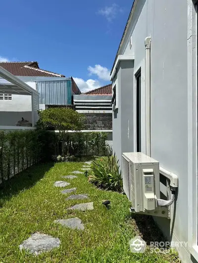 Charming side garden with stepping stones and air conditioning unit, perfect for relaxation.