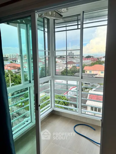 Bright enclosed balcony with panoramic city views and sliding glass doors.