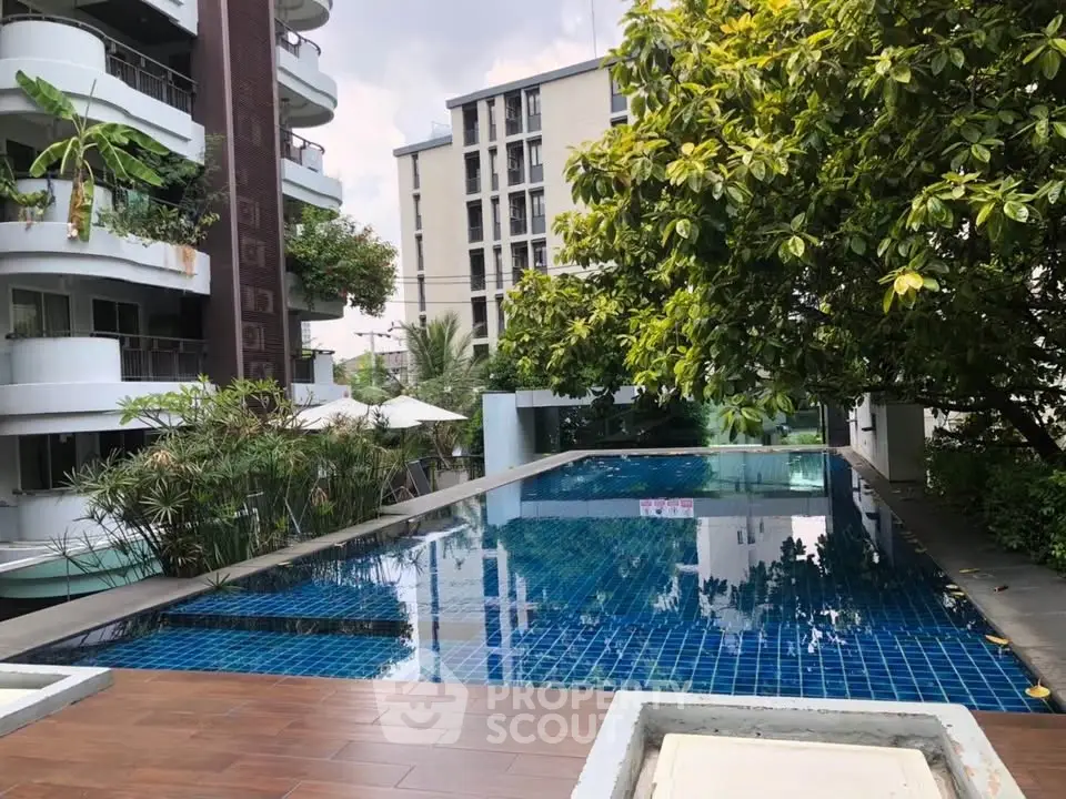 Luxurious apartment complex with serene pool and lush greenery, perfect for relaxation and leisure.