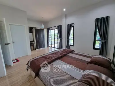 Spacious bedroom with modern decor and large windows offering natural light.