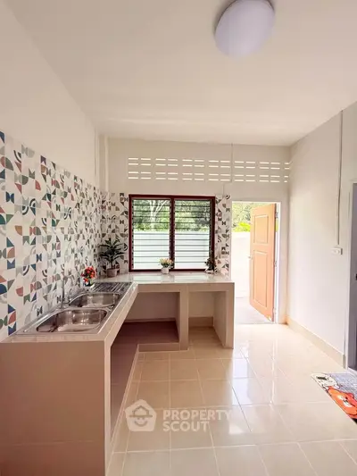 Bright kitchen with patterned backsplash and dual sinks, featuring an open layout and natural light.