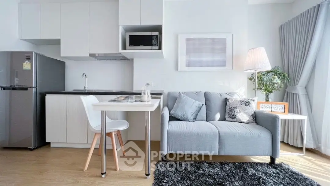 Modern living room with sleek kitchen, cozy sofa, and stylish decor in bright, airy apartment.