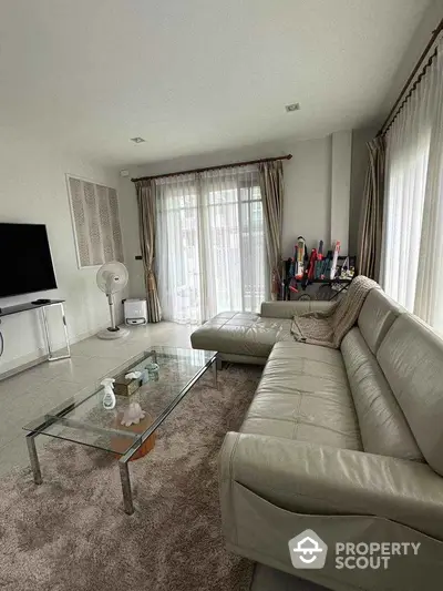 Spacious living room with modern leather sofa and glass coffee table, perfect for relaxation.