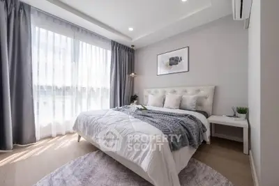 Elegant bedroom with natural light, featuring a plush bed and modern decor, perfect for relaxation.