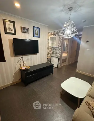 Modern living room with stylish decor and wall-mounted TV in cozy apartment.