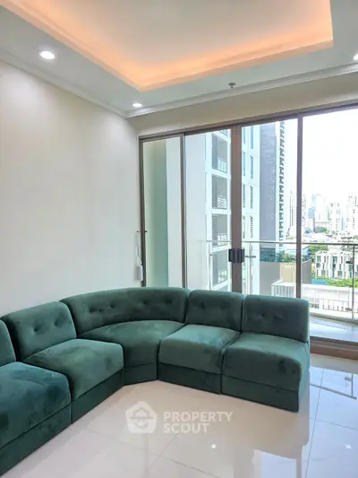 Modern living room with green sectional sofa and city view balcony in luxury apartment.