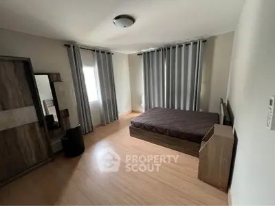 Spacious bedroom with modern furnishings and large windows for natural light.