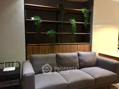 Modern living room with stylish gray sofa and wooden shelving adorned with greenery.