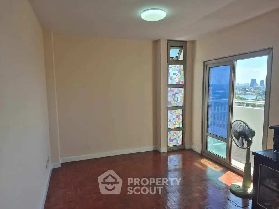 Spacious living room with parquet flooring and balcony access, featuring a stained glass window for added charm.